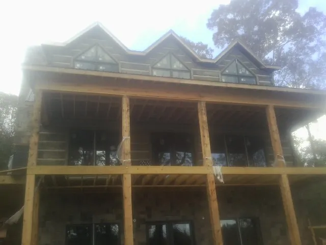 Dormers and porch framing on a large log home under construction — Roof Coating work by our crew in Putnam Valley