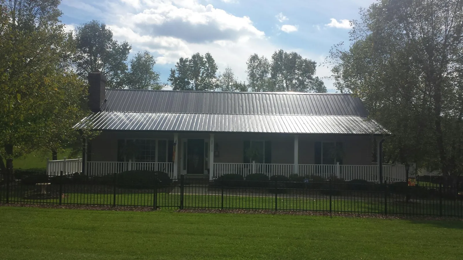 Gray metal roof on a brick ranch with a full width front porch — Gutter Guard Installation work by our crew in Putnam Valley