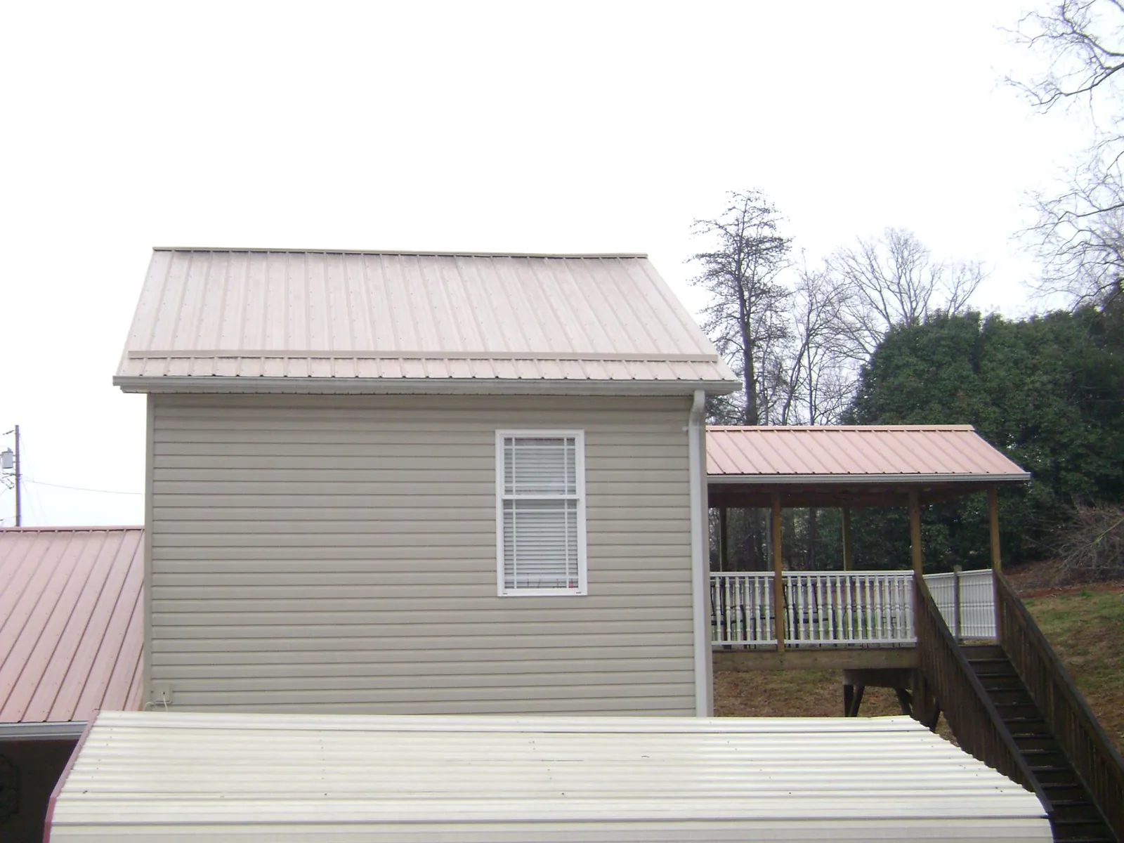 Tan metal roofs on a two story addition and attached porch, from a Roof Replacement job in Putnam Valley