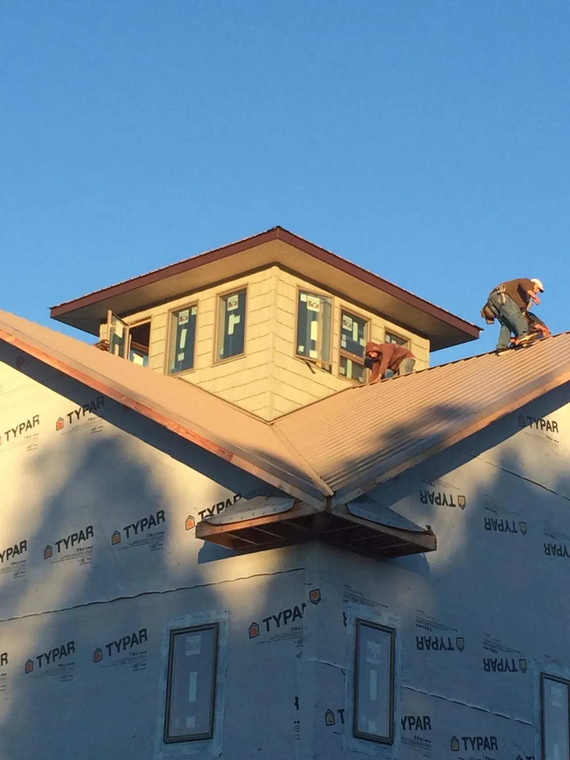 Roofers working around a rooftop cupola on a new metal roof at sunset — Roof Waterproofing in Putnam Valley by Roofing Brothers